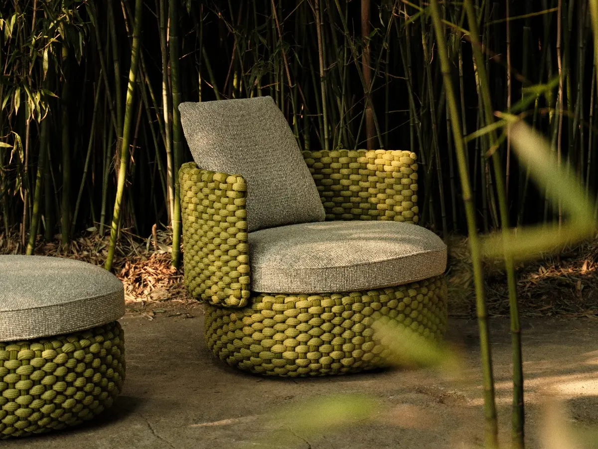 Poltrona lounge girevole e Pouf della collezione Oleia, in un ambiente all'aperto