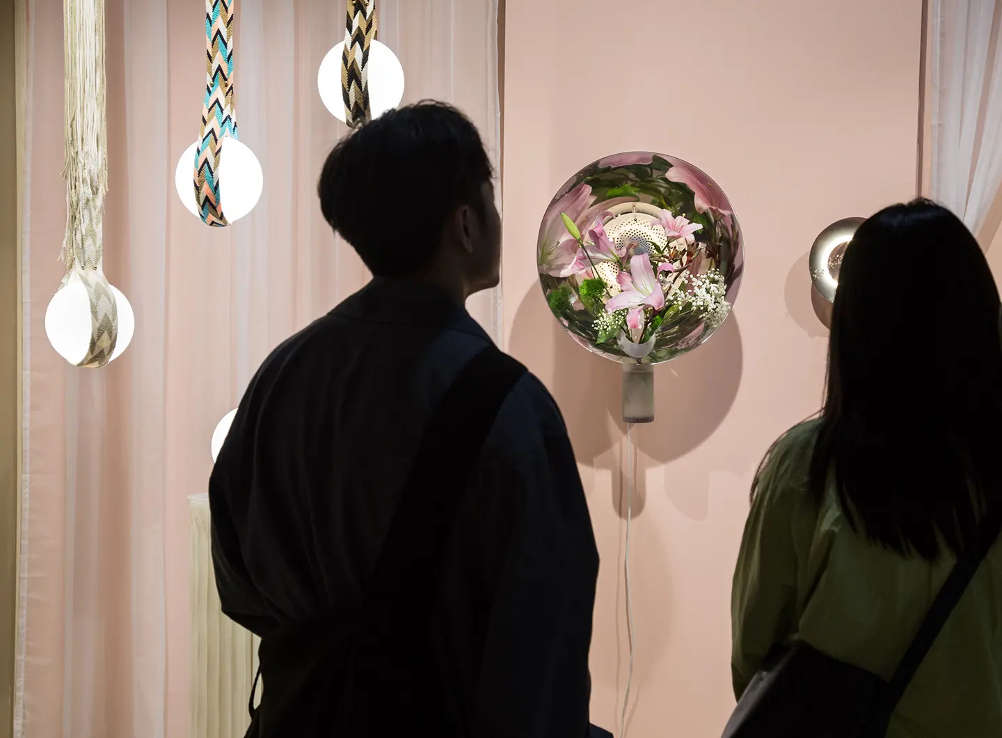visitatori che osservano lampade in vetro con fiori all'interno