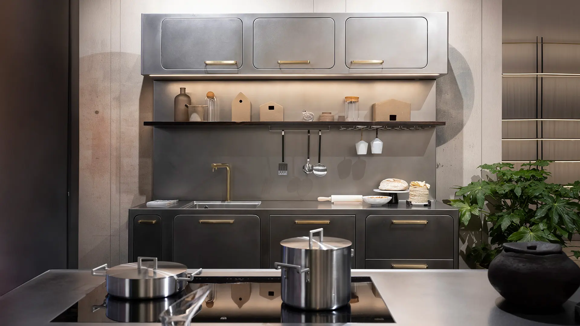 Cucina in acciaio con isola su cui sono posti i fuochi a induzione